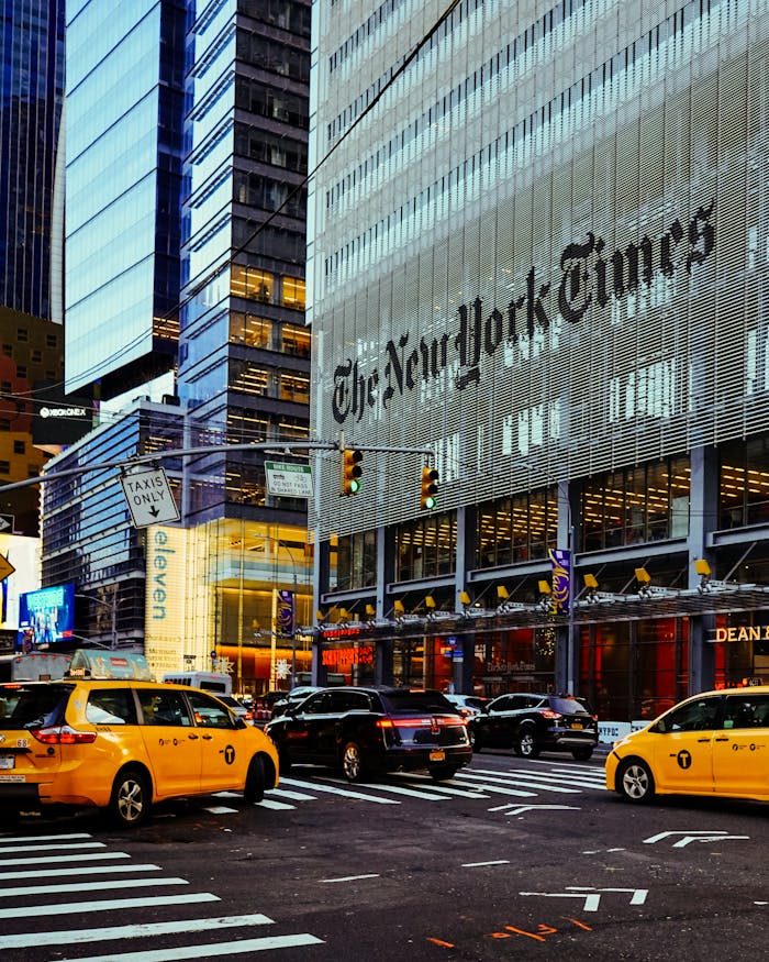 hero-img-01 Street view of the New York Times Building surrounded by taxis in bustling New York City.