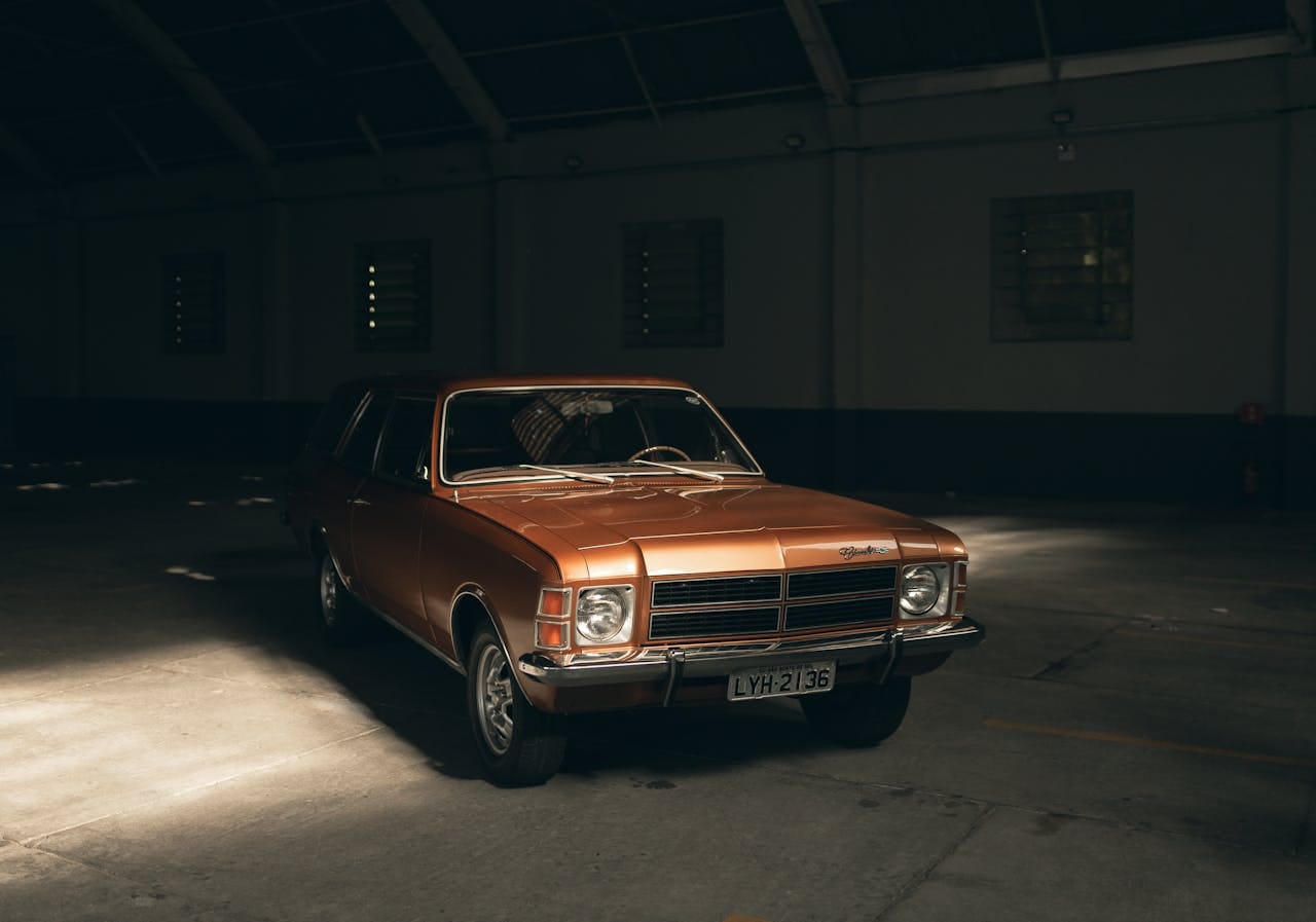 gallery-2 Classic brown vintage car parked in a shadowy indoor garage.