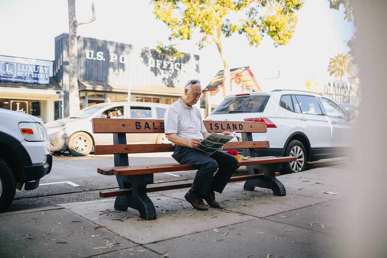about-01 An elderly man enjoys a newspaper while sitting on a bench on Balboa Island during a sunny day.